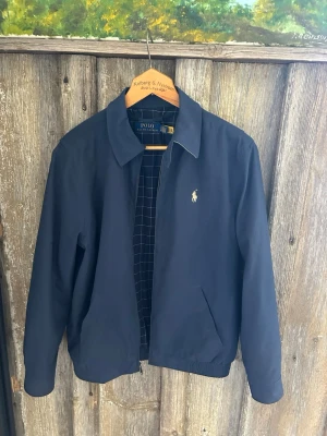 Polo Ralph Lauren Harrington Jacket – Navy - Snygg Polo Ralph Lauren jacka i marinblått 🔵  ✨ Klassisk och stilren modell 🏷️ Polo Ralph Lauren 🎨 Färg: Navy / mörkblå 📦 Fint skick – se bilder för skick och detaljer  Skickas och packas snabbt📦 Hör gärna av dig vid frågor!
