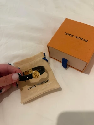 Louis Vuitton armband - Louis Vuitton armaband som är i svart men även kan byta sida till brun. Kommer med original ask och dustbag.