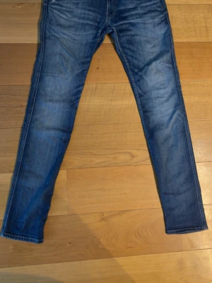 Replay anbass - Snygga blå slim fit jeans med lätt slitningar och tvättade detaljer. Klassisk femficksmodell med raka ben och normal midja. Perfekta till en avslappnad stil och passar till det mesta. Tillverkade i denim med skön stretch. Står 34w men skulle säga 32/33