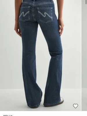 Mörkblå bootcut jeans med kontrastsömmar - Snygga mörkblå bootcut jeans med vita kontrastsömmar och dekorativa fickor bak. använda 2 ggr och säljer pga dom blivit försmå. hör av er vid frågor, pris kan diskuteras 