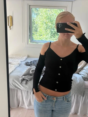 Svart festtopp med knappar - Super cool topp med ”utskurna” axlar o fake knappt längs mitten. Stretchigt material och axelbanden är justerbara. Köpt på sellpy o använd 2 gånger🥰🥰