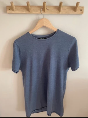 Blå t-shirt från Zara Man - En stilren blå t-shirt från Zara Man i storlek S. T-shirten har rund halsringning och korta ärmar. Den har ett skönt, tunt tyg. Perfekt basplagg till garderoben. Använd vid ett tillfälle. 