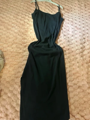 Svart ribbad midiklänning från Amisu - Svart ribbad midiklänning från Amisu med tunna axelband och figurnära passform. Klänningen har en enkel och stilren design som passar perfekt till lager på lager eller som den är. Materialet är mjukt och stretchigt för extra komfort.