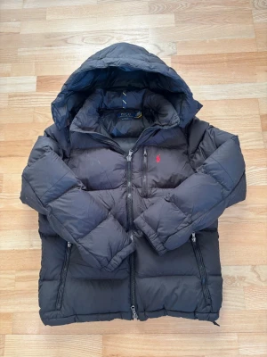 Ralph Lauren jacka - Hej, säljer nu min gamla vinterjacka från Ralph Lauren! Det är en svart Ralph Lauren puffer jacka i storlek M. Den har varit med om ett par vintrar men fortfarande i fint skick! Dunet är ganska slitet men det är typ det ända. Hör av er vid frågor och pris ej hugget i sten!😁