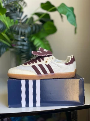 Beige och bruna sneakers med ränder - Snygga sneakers från Adidas i beige mocka med mörkbruna detaljer och klassiska tre ränder på sidan. Skon har brun sula i gummi och matchande bruna skosnören. Perfekt för dig som gillar retrostil och vill ha något som sticker ut.