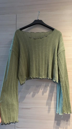 Olivgrön croppad stickad tröja - Olivgrön stickad tröja med croppad passform och vida ärmar. Ribbstickad struktur i supermjukt och stretchigt material. Köpt i Sydkorea, därav inget märke.