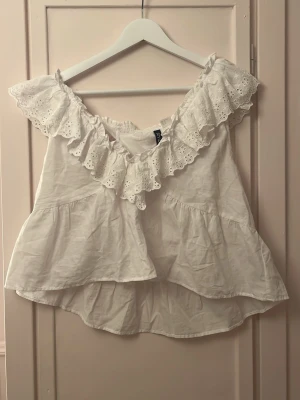 Vitt linne med volang - Söt vitt linne med bred volangkant i broderad spets. Luftig modell med dubbla lager tyg och romantisk känsla. Sminkfläck under volangen, men som täcks av volangen och inte synns när man har den på sig! 
