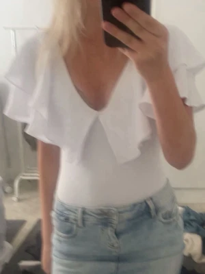 Vit Zara body - Säljer denna vita bodyn från Zara i storlek s, med v ringning och volang detalj🥰använd runt 5 gånger och inga defekter.