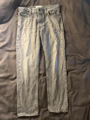 Ljusgrå raka jeans - Snygga ljusgrå jeans med rak passform och klassisk femficksdesign. Jeansen har en enkel look med normal midja och subtil tvätt för en avslappnad vibe. Perfekta till sneakers eller boots och passar till många olika stilar.