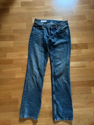 Blå raka jeans från Zara - Säljer ett par klassiska blå jeans från Zara med rak passform och fem fickor. Jeansen har normal midja, dragkedjegylf och bälteshällor. Tillverkade i slitstark denim som passar perfekt till en avslappnad stil.