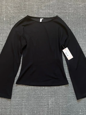 Svart långärmad topp - En stilren svart långärmad topp med rund halsringning och som sitter lite tajtare i midjan. Toppen har en enkel och clean design som passar till det mesta. Ny med prislapp! Från Nelly i storlek S.