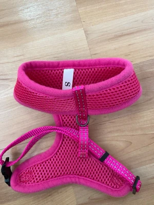 Dogman hundsele rosa S - Säljer en Dogman hundsele i meshmaterial för husdjur, storlek S. Halsmått 25cm, bröstmått 36-50cm. Selen är oanvänd. Selen har justerbara band, reflexdetaljer och ett metallfäste för koppel. Perfekt för promenader med mindre hundar. 
