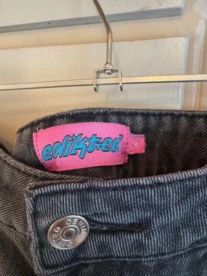Svarta wide leg jeans från Edikted - Säljer ett par gråa jeans från Edikted med breda ben och låg midja. Jeansen har klassisk femficksdesign, silverfärgade detaljer och är gjorda i denim. Perfekta för en avslappnad och trendig look.