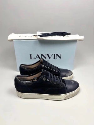 Mörkblå sneakers från Lanvin - Lanvin DBB1 Sneaker Navy | Modell: DBB1 | Skick: Begagnat skick (slitage finns, se bilder) | Nypris: 4999 kr | Storlek: 9 UK / 43 EU | Creaseskydd sitter i skorna och redo att användas | Skobox, extra skosnören och dustbags medföljer | Hör av dig vid minsta fundering 📦