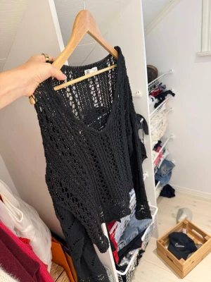 Svart virkad tröja från Zara - Snygg svart virkad stickad tröja från Zara med vid passform och djup v-ringning. Tröjan har långa ärmar och ett luftigt, genombrutet mönster som ger en trendig look. Perfekt att styla över ett linne eller bikini.