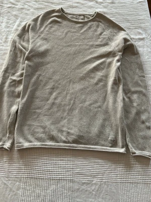 Beige stickad tröja Jack & Jones - Snygg beige stickad tröja från Jack & Jones med rund halsringning och lång ärm. Tröjan har en diskret struktur i materialet och en enkel, stilren design som passar till det mesta. Perfekt för lager på lager och enkel att matcha.