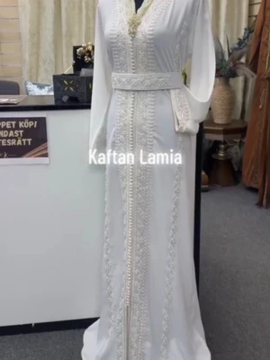 Vit Kaftan  - Elegant vit kaftan med vackra broderade detaljer. Klänningen har ett matchande bälte i midjan och långa, vida ärmar. 