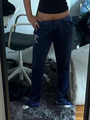 Mörkblå mjukisbyxor Juicy Couture - Säljer ett par mörkblå mjukisbyxor från Juicy Couture med dragsko i midjan och logga på ena benet. Byxorna har raka ben och är gjorda i ett mjukt, skönt material som känns lyxigt. Perfekta för chill dagar eller när du vill vara extra comfy.  Passar som xs - s skulle kunna passa till ish 38 också  då de är väldigt stretchiga köpta för 1200