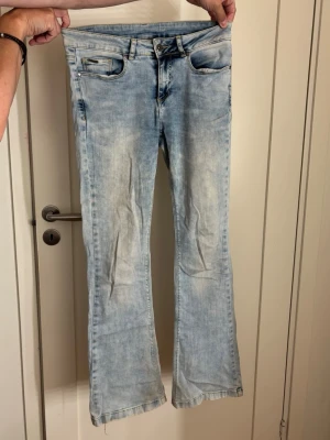 Ljusblå bootcut jeans med slitningar - Säljer ett par ljusblå bootcut jeans med råa kanter nertill. 