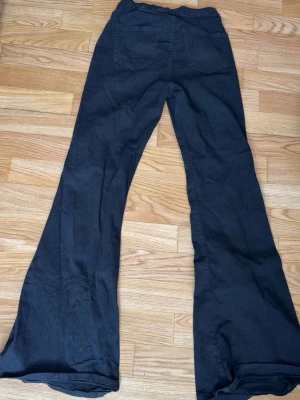 Svarta bootcut jeans med fickor - Säljer ett par svarta bootcut jeans med två bakfickor och knappstängning fram. Jeansen har en klassisk passform med utsvängda ben och är perfekta för dig som gillar en retrostil och vill ha långa jeans Materialet känns mjukt och stretchigt, vilket gör dem bekväma att bära hela dagen. Använt få gånger 