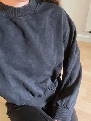 Svart sweatshirt - En svart oversized sweatshirt med rund halsringning och ribbade muddar vid ärmar och midja. Tröjan är enkel och stilren, perfekt att matcha med jeans eller leggings. Tillverkad i mjukt material för en avslappnad look.