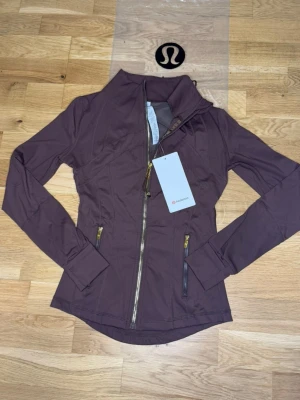 Brun Nulu define jacket Lululemon Stl.4 - Den lite mindre och smalare versionen av lululemons define jacket I Stl 4 som motsvarar runt S eller en riktigt tight M. Jag hade rekommenderat S för bäst passform. Den är helt oanvänd och ren!💞💞