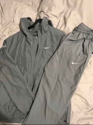 Grå Nike nummer  - Säljer ett grått träningsset från Nike med jacka och byxor. Settet är för litet för mig har använt 3-5 gånger som ny 