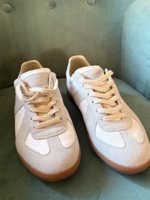 Vita maison margiela sneakers - Maison margielas i mycket bra skick, har bara använts till när man ska haft klätt upp sig. De är bekväma att ha på sig och passar i storlek mellan 44-45