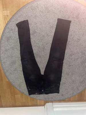 Svarta slim jeans från Replay - Säljer ett par svarta slim jeans från Replay med klassisk femficksdesign och diskret logga på myntfickan. Jeansen har smal passform och är tillverkade i stretchigt denimtyg för en bekväm känsla.