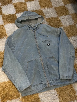 Sweet sktbs blå jeansjacka - Snygg ljusblå jeansjacka med dragkedja och huva. Jackan har två stora fickor framtill, en mindre bröstficka med dragkedja och en liten patchdetalj. Avslappnad passform och diskret mönster i tyget för en cool look.
