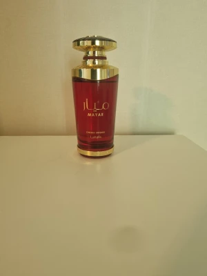 Mayar Cherry Intense parfym - Pris kan diskuteras! Mayar Cherry Intense från Lattafa är en lyxig parfym i en elegant röd glasflaska med guldiga detaljer och lock. Flaskan har en modern, stilren form och text i guld. Perfekt för dig som gillar exklusiva och fruktiga dofter. Halvt full! Pris kan diskuteras
