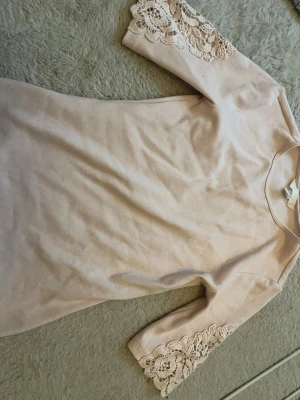 Ljusrosa T-shirt  med spetsdetaljer - Söt ljusrosa klänning i ribbad bomull med fina spetsdetaljer på. Perfekt för sommarens alla tillfällen. Är i storlek xs från h&m