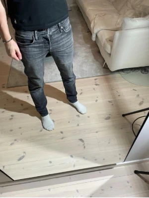 Mörkgrå jeans från Jack & Jones - Säljer ett par svarta jeans från Jack & Jones med rak passform och klassisk femficksdesign. Jeansen har en lätt tvättad look och är tillverkade i bomull med lite stretch för extra komfort. Perfekta till en avslappnad stil.