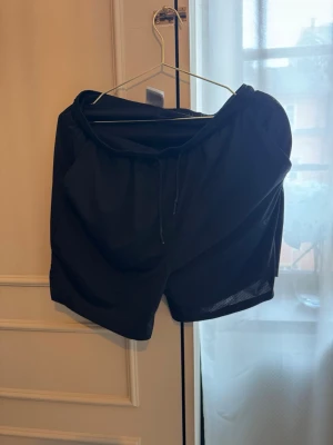 Svarta träningsshorts från ICANIWILL - Svarta träningsshorts från ICANIWILL med elastisk midja och snörning. Lätta och luftiga, perfekta för gymmet eller löprundan. Klassisk design utan extra detaljer för en clean look.