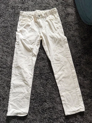 Vita raka jeans från Kappahl - Snygga vita jeans med rak passform från Kappahl. Klassisk femficksmodell med bälteshällor och silverfärgade nitar. Perfekta för en fräsch och stilren look. passar till många olika outfits. Dock en liten svart fläck på bakfickan  