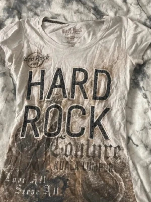 Hard Rock Café t-shirt med tryck - Cool t-shirt från Hard Rock Café med stort tryck framtill i svart och brunt. T-shirten är kortärmad och har rund hals. Materialet känns som bomull och passformen är normal. Perfekt för dig som gillar statement-plagg och musikvibe.