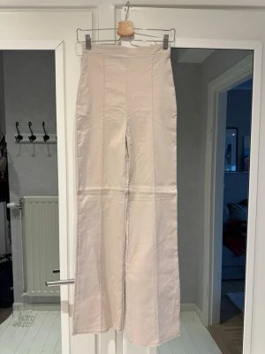 Beige byxor från NLY One - Beige byxor från Nelly. Storlek XS. Byxorna har hög midja, vida ben och markerade sömmar framtill. Stretchiga. Aldrig använda.