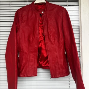 Röd läderjacka - Supersnygg, populär röd vintage läderjacka säljes (äkta läder) fint skick. Strl: 36. Liten svart fläck i kragen, se andra bild. 