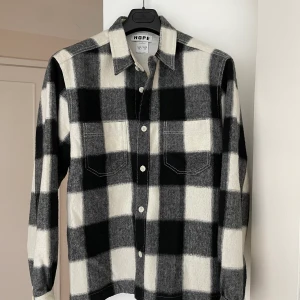 Hope Flanell overshirt  - Svart-och vitrutig overshirt i flanell från Hope. Endast använd ett fåtal gånger så är i mycket fint skick! Riktigt snygg som vårjacka! Storlek 46 men lite oversized passform, funkar till herr och dam🤝🏻