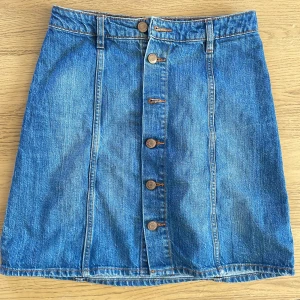 Kort blå jeanskjol - Klassisk jeanskjol med knapar! Går att ha den i normal midjehöjd eller som högmidjad. Kort men inte mini mini utan slutar en bit ovanför knäna