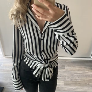 Blus/skjorta - Blus med snören som går att knyta framåt eller bakåt, från NA-KD storlek 32 (xxs). Fint skick, knappt använd.