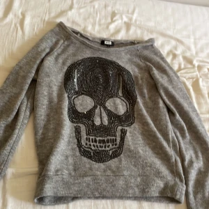 Säljer denna stickade tröjan på grund av ingen andvänding  - Det är en stickad tröja med en dödskalle på den är grå och den har svarta paljetter på 