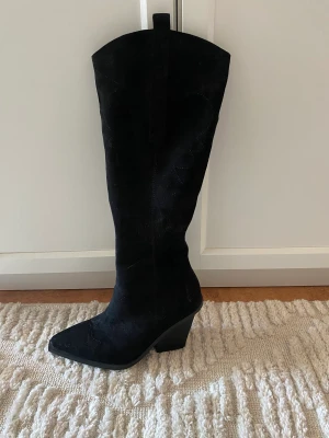 Cowboy stövlar - Svarta stövlar i mocka i wide fit från RAID. Endast använda en gång. I storlek 39. Nypris 939kr. Klackhöjd: 9,5 cm.