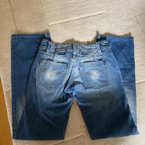 Vintage Levi's - Vintage raka lågmidjade Levi's jeans med coola detaljer. Kan skicka några fler bilder men får tyvärr inte dem över rumpan så inga bilder med dem på. Midjemåttet tvärs över 34cm. Innerben runt 75cm. Står 27/32 men skulle snarare säga att det passar W25. 