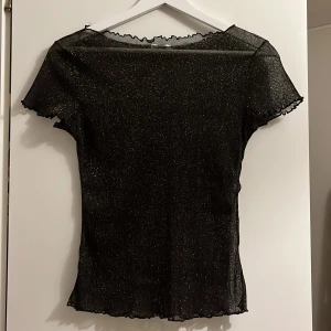 Meshtopp Chiquelle - Glittrig meshtopp med volangdetaljer från Chiquelle i Strl M. 