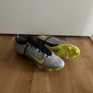 Nike Air Zoom Mercurial Vapor 15 Elite FG XXV - Silver/Neon/Svart - Säljer då dem är för stora. Dem är använda en träning och är fof i jätte bra skick. Kan diskutera pris vid snabb affär. Nypris 3149