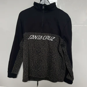 Santa Cruz fleece tröja - Tröja från Santa Cruz. Svart och med leopard mönster på nedre delen. Storlek S för män 