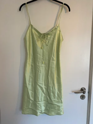 Somrig satinklänning - Satinklänning i oanvänt skick med söta snören fram. Medellång 