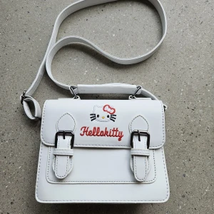 Hello Kitty handväska  - Oanvänd handväska Hello Kitty i skinn (eller skinnimitation, vet ej). 19x16 cm