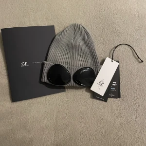 C.p company mössa - Tjo säljer min grå cp company mössa, det är nya versionen. Den är i väldigt bra skick 9/10 Passar alla (one size) Äkta, har äkthets bevis kvar! Nypris ca 1200kr Hör av dig vid frågor! 